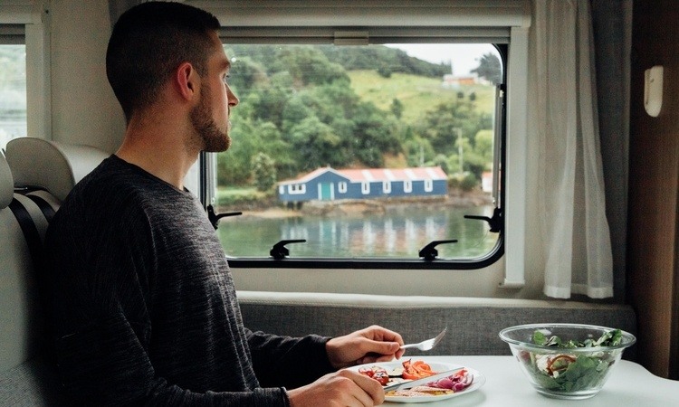 A man enjoying a meal in his Wilderness motorhome while freedom camping