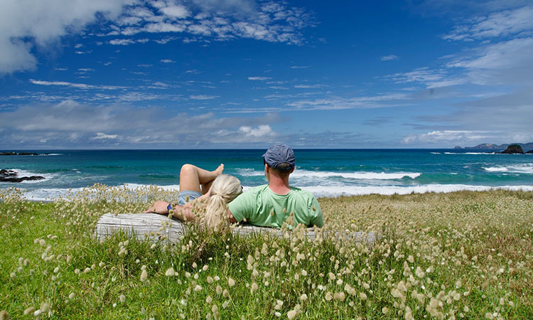 A couple relaxing at a beach on a long summer day in New Zealand