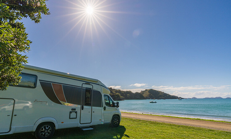 A motorhome parked up infront of a beach on a sunny day