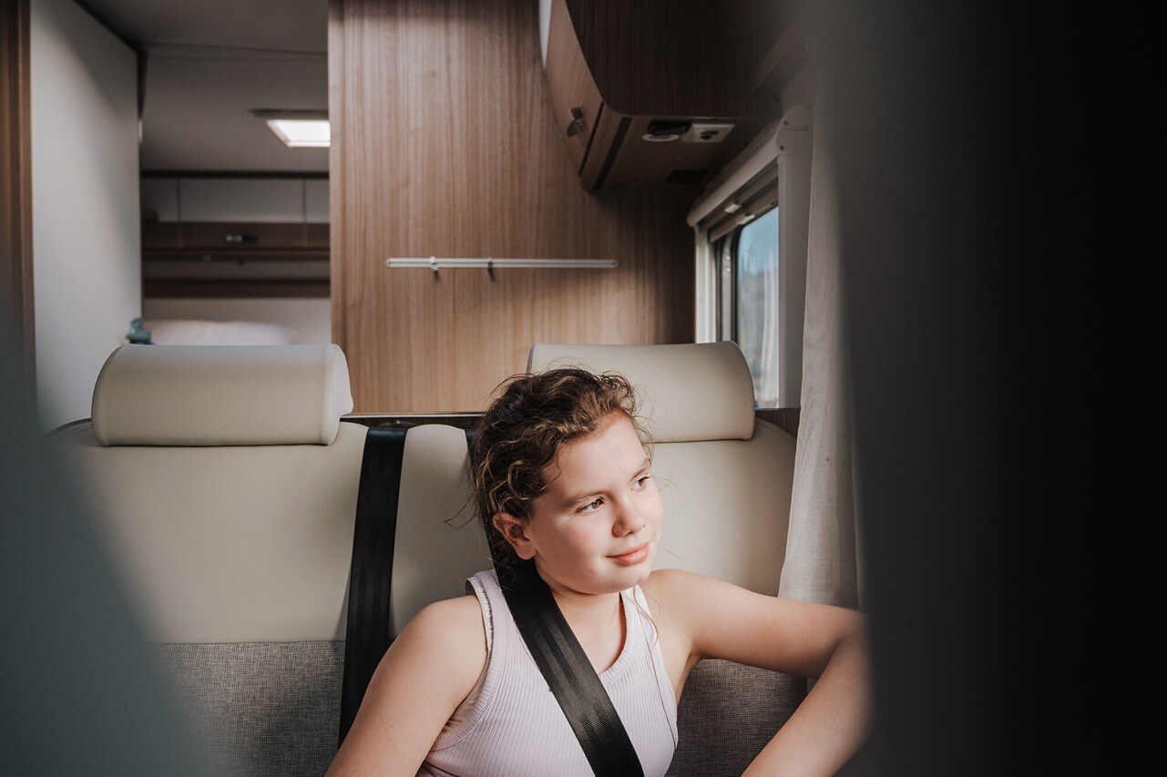 Kid sitting at the passnger seat of a motorhome with a seatbelt