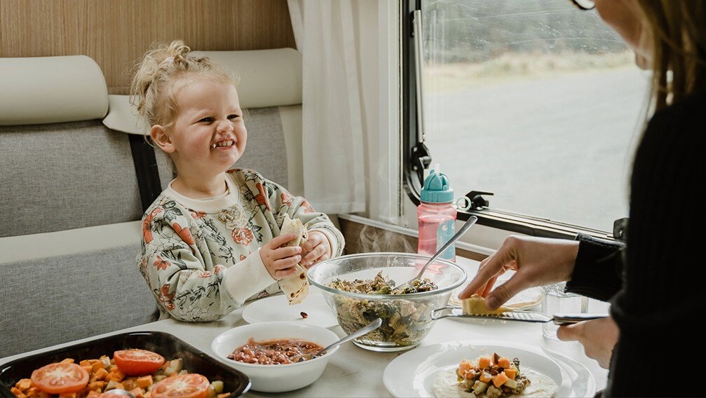 A child enjoying her food in the motorhome dining area