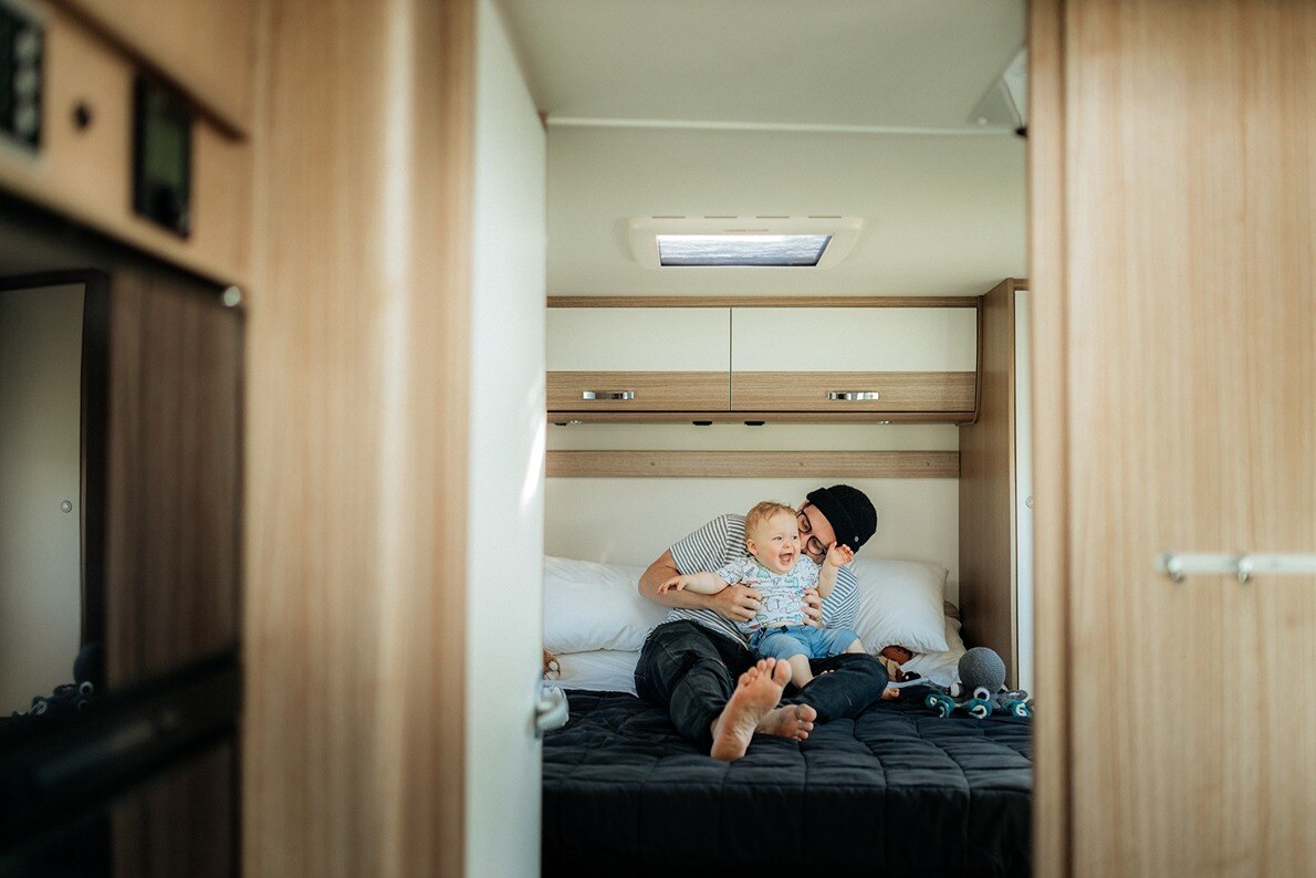 Dad and baby playing around in a motorhome bedroom