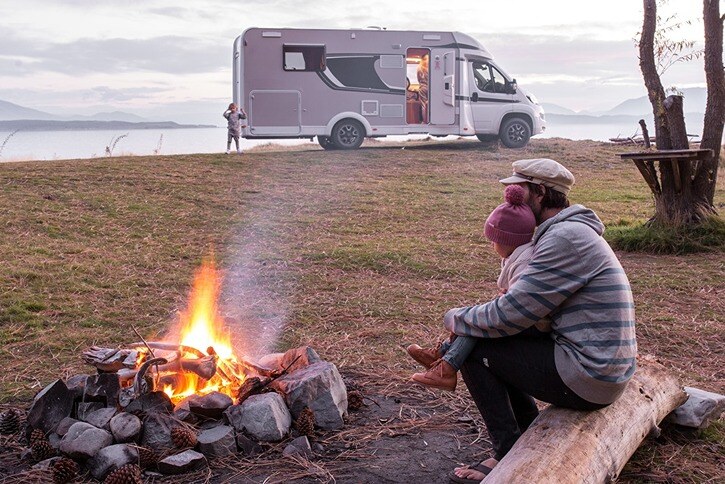 Family sitting beside a campfire at their motorhome campsite