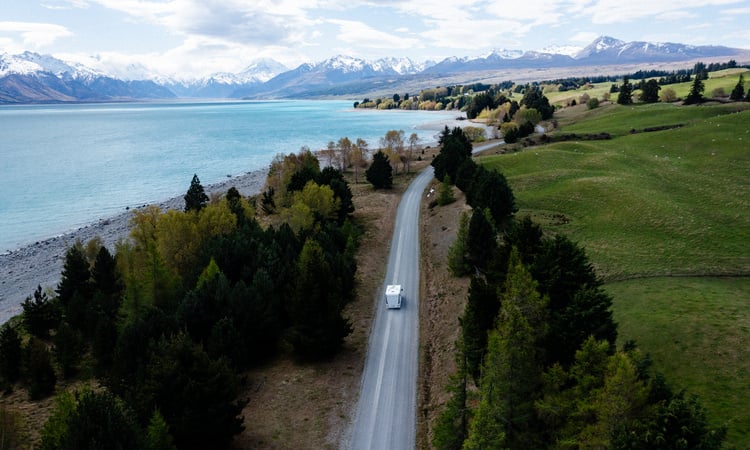 A Wilderness Motorhome being driven on a road with a scenic New Zealand view in the background 