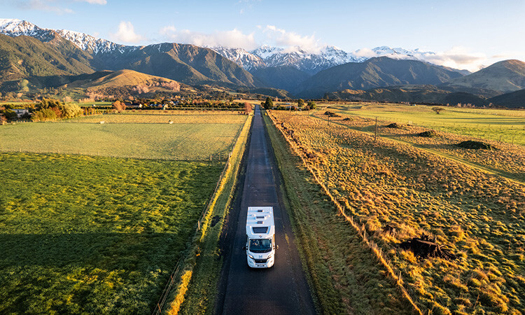 A Wilderness Motorhome being driven on a road with a scenic New Zealand view in the background.