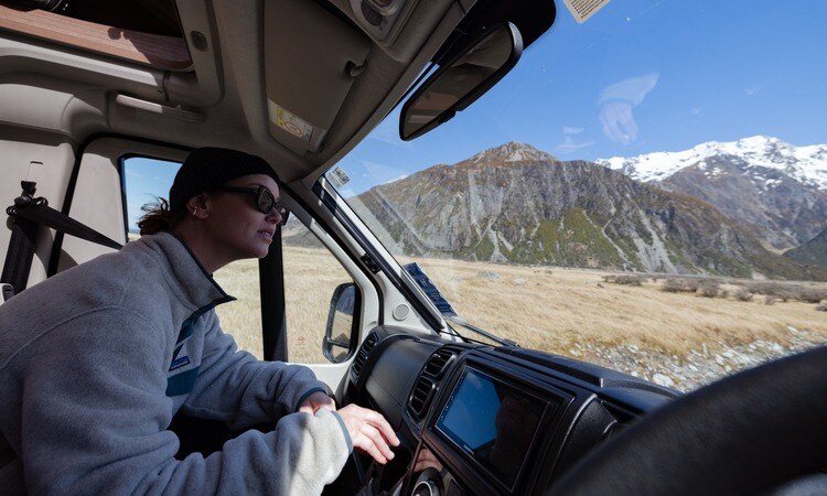 A traveller admiring the New Zealand landscape from inside her motorhome